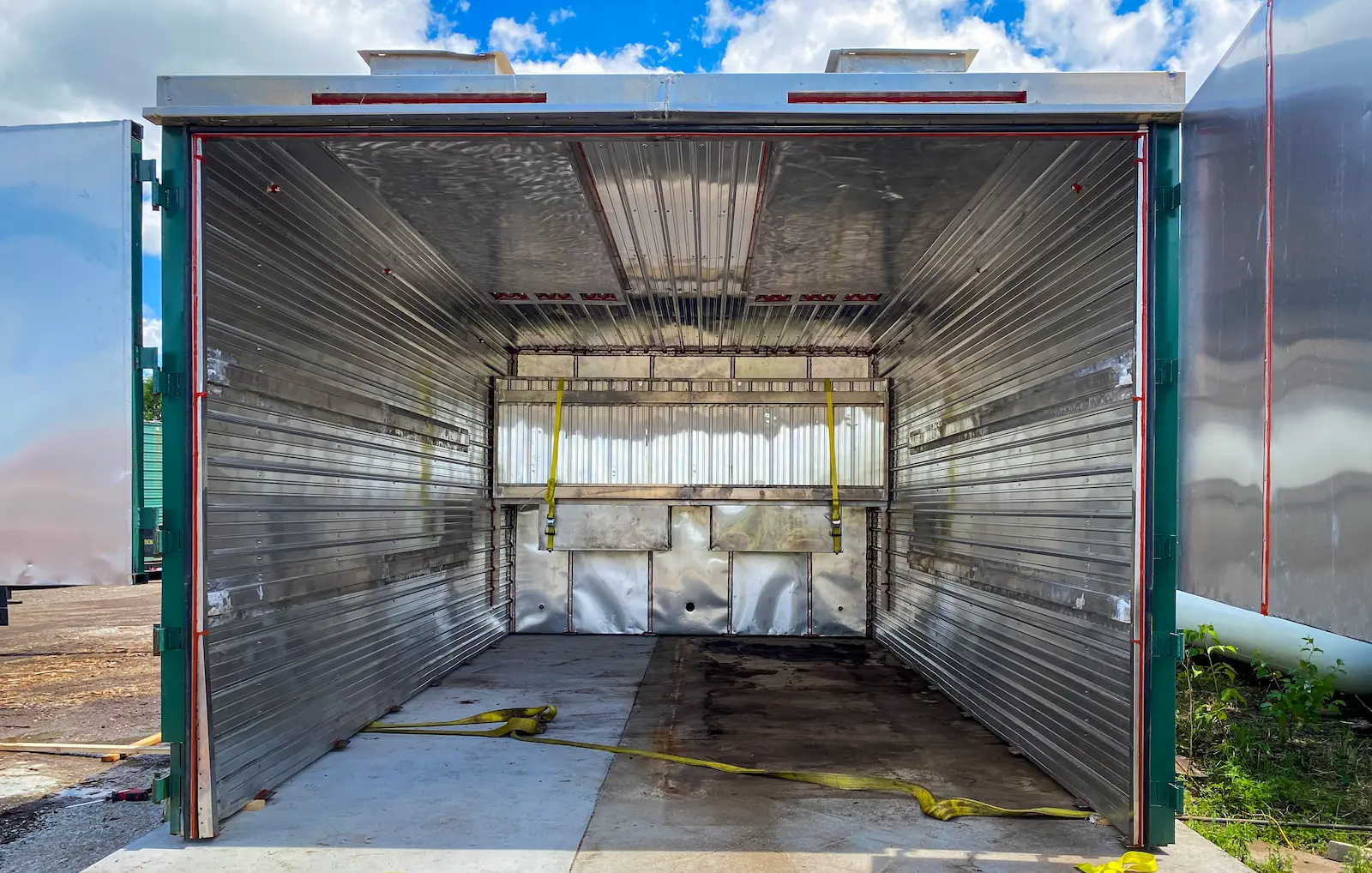 Interior of an empty firewood kiln chamber at Best Burn Firewood, showing insulated steel walls and ceiling, the insulated rear barrier, and roof exhaust fans, New Berlin, Wisconsin
