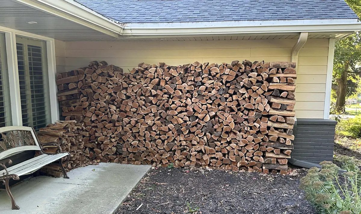 full cord of firewood stacked neatly against the side of a home in Wisconsin showing 8 foot wide 4 foot high stack