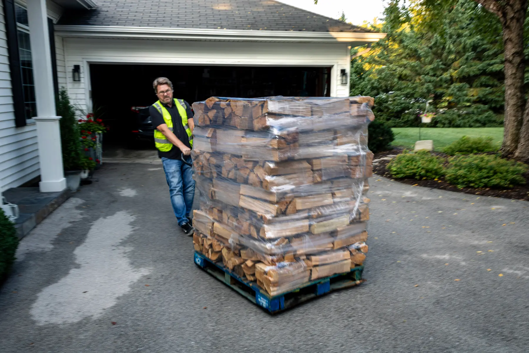 Best Burn Firewood driver moving a pallet of firewood bundles into a garage with a pallet jack