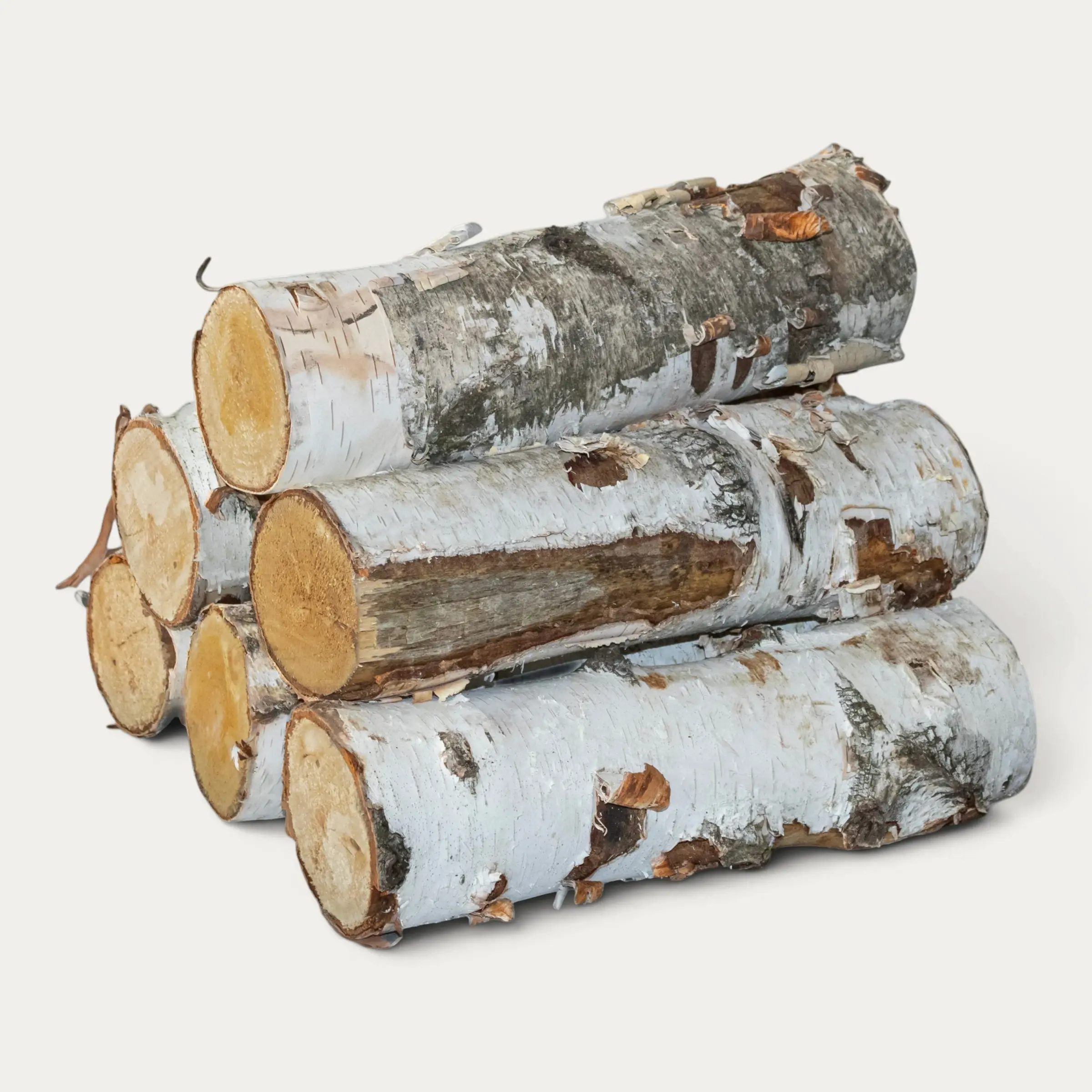 Side view of white birch decorative logs stacked in layers with peeling bark and visible cut ends