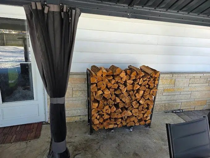 half face cord of oak firewood stacked in a rack against a house wall